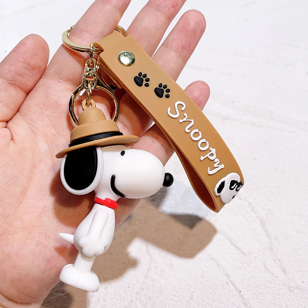 Snoopy silicone keychain with brown hat and matching brown strap held in a hand on a light background