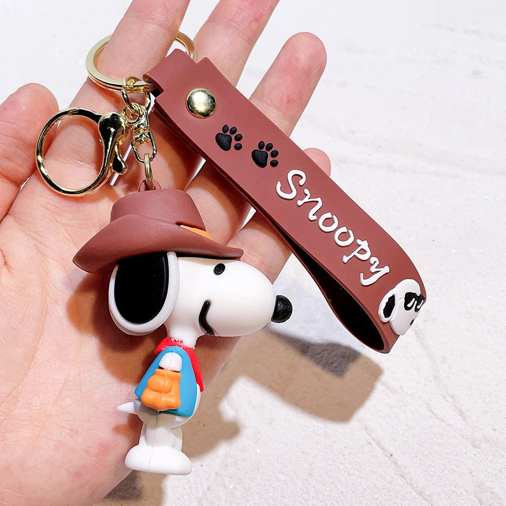 Snoopy silicone keychain with brown ‘Snoopy’ strap held in a hand on a white background