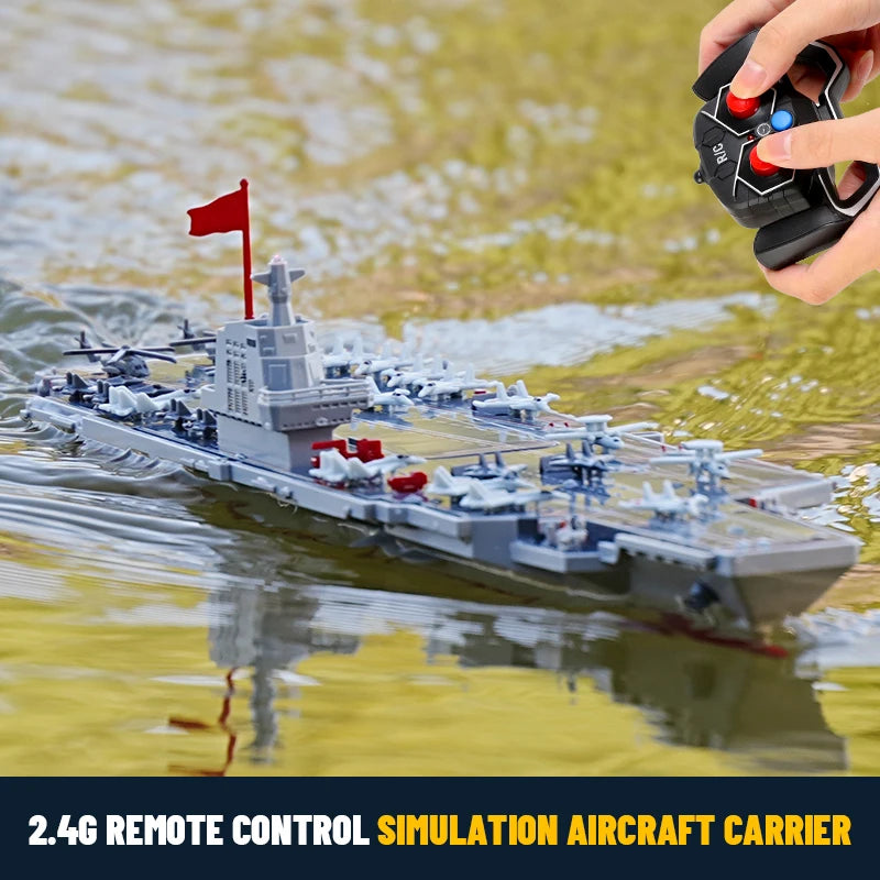Model of a remote-controlled aircraft carrier with a person holding a remote control over water.